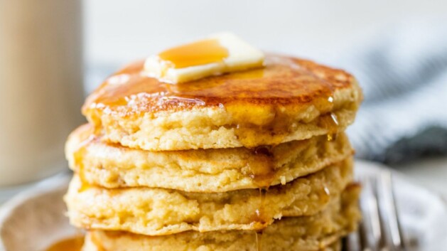 Thick pancakes stacked and topped with butter and maple syrup.