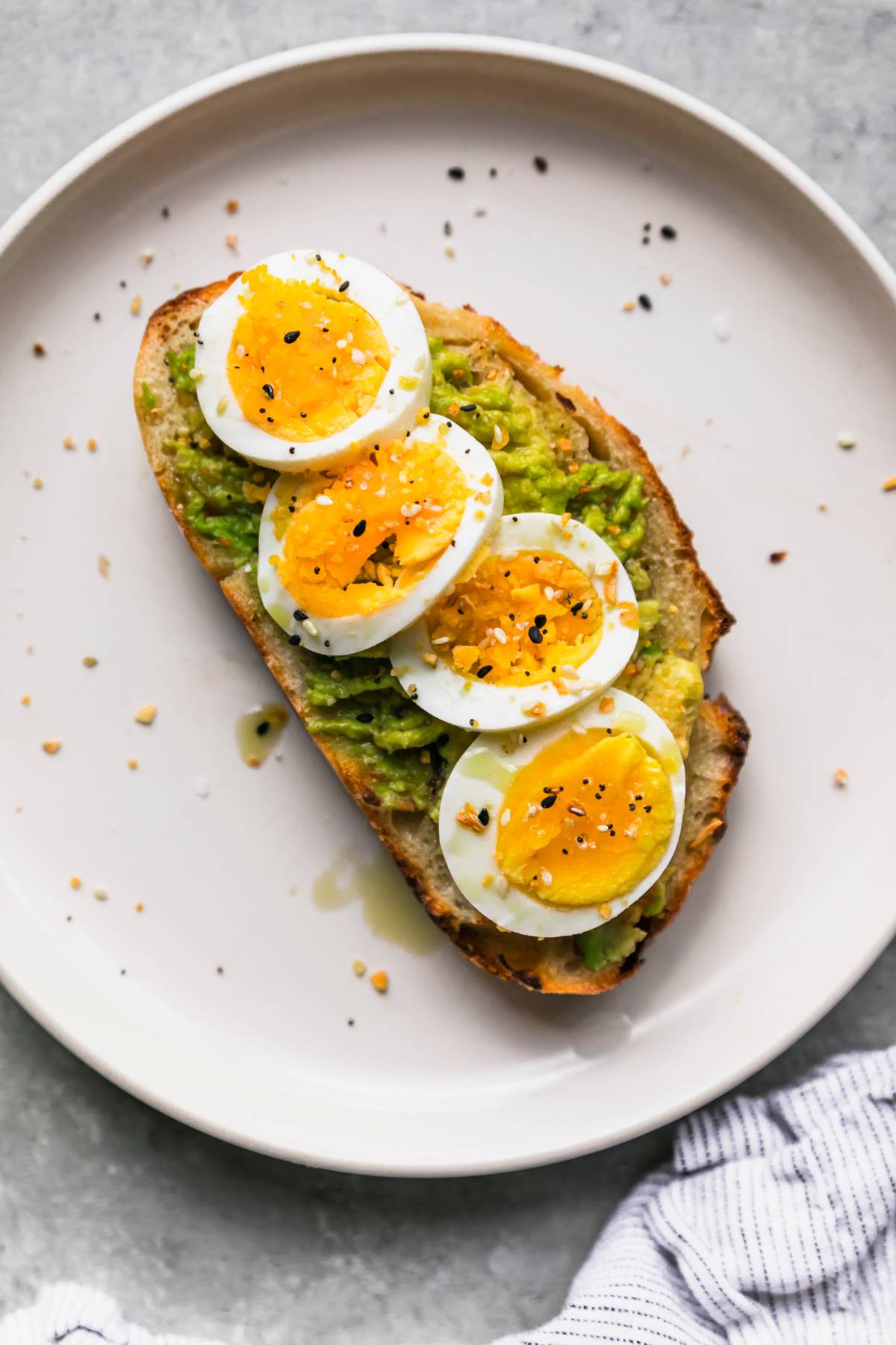 Avocado toast with hard boiled egg on a white plate.