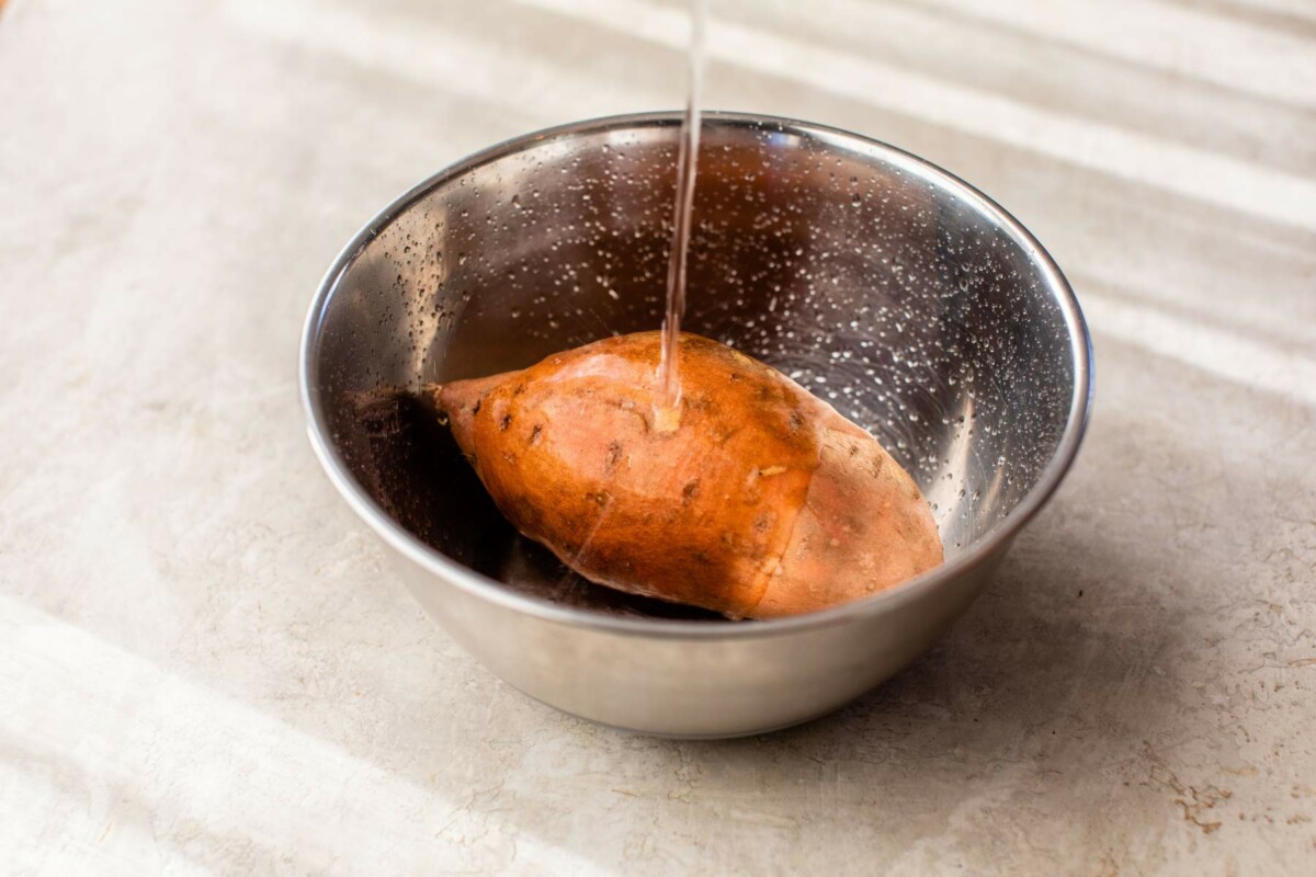 Rinsing a sweet potato off with water.