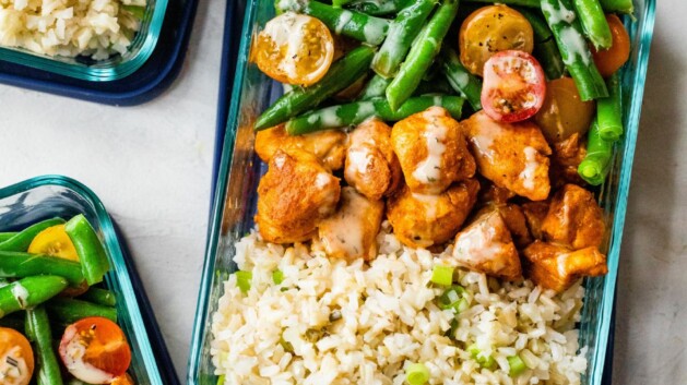 Buffalo chicken rice bowls divided into glass storage containers.