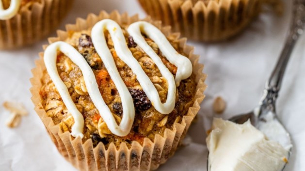 Carrot cake baked oatmeal cups topped with a drizzle of cream cheese icing.