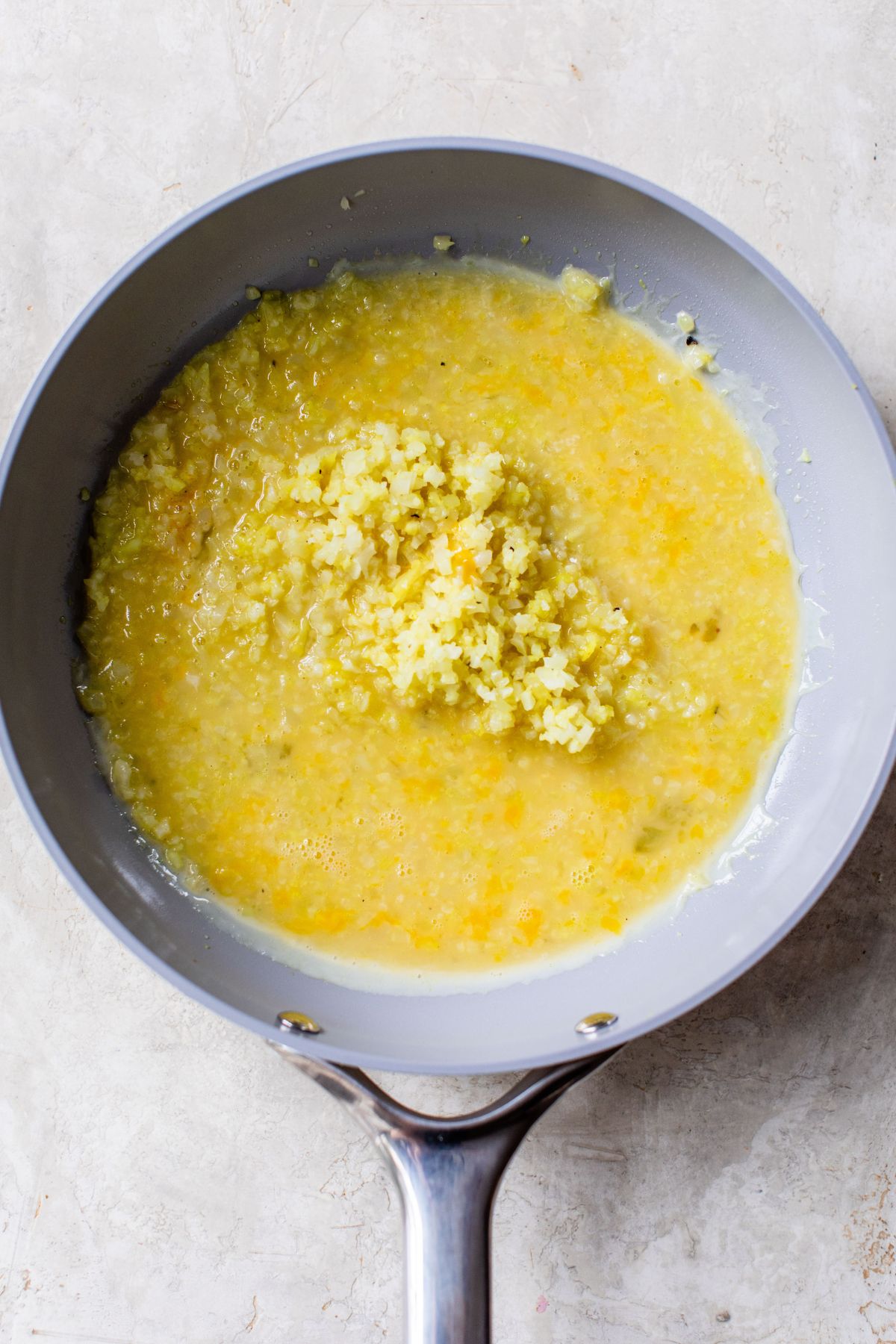 Riced cauliflower mixed with eggs in a pan.