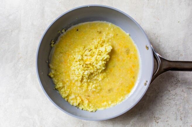 Riced cauliflower mixed with eggs in a pan.