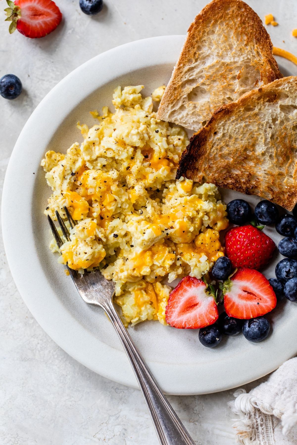 Scrambled eggs with cauliflower served with berries and toast.