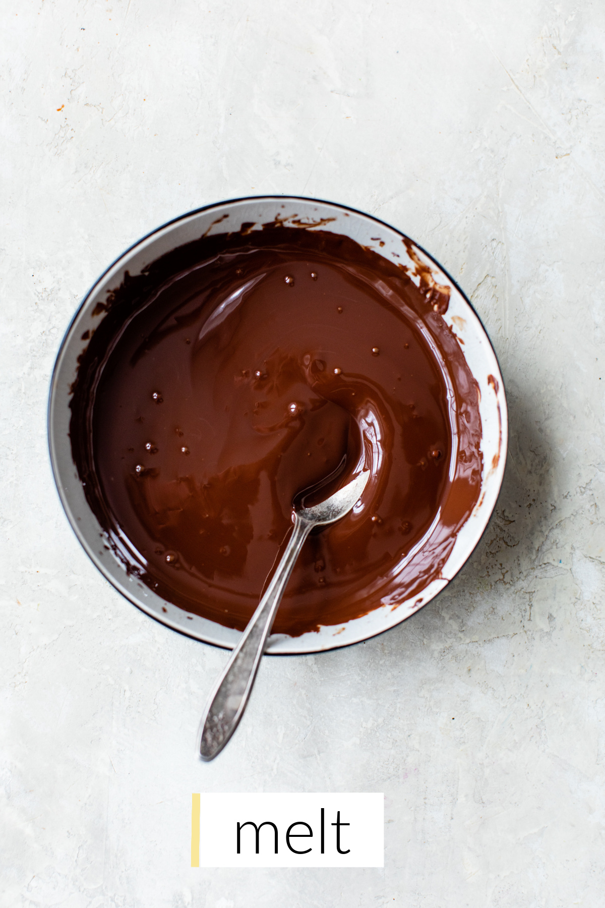 melted dark chocolate and coconut oil in a small white bowl with fork.