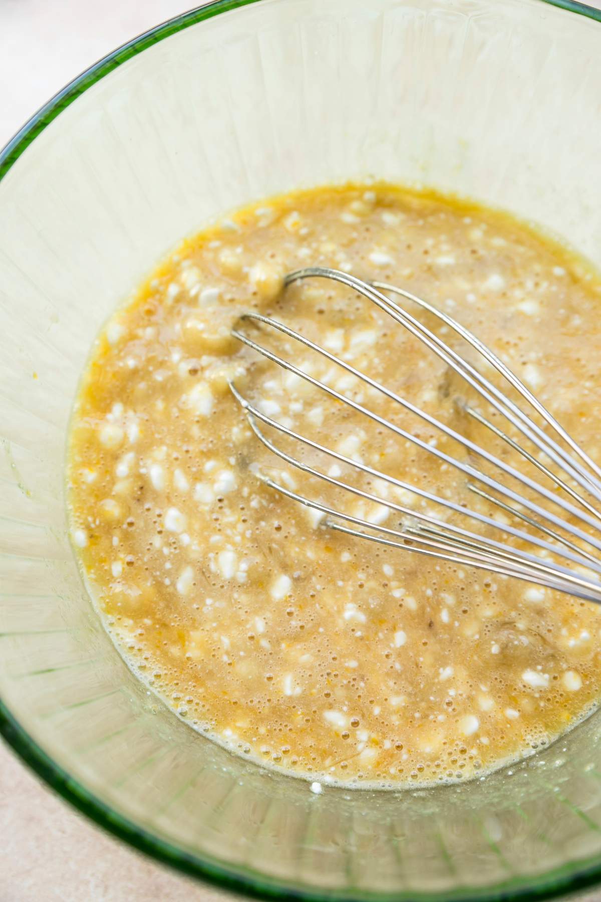Using a whisk to mix mashed banana, egg and cottage cheese.