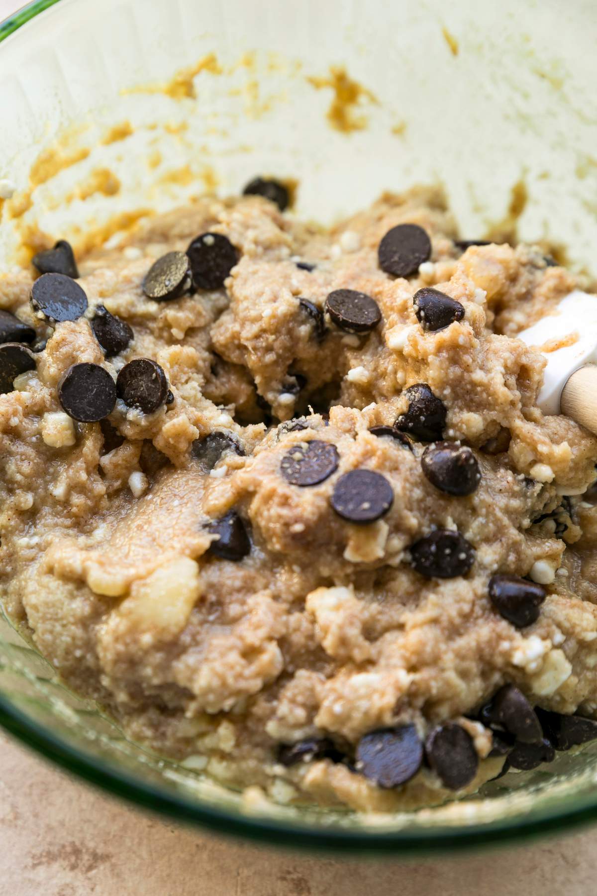 Mixing almond flour and cinnamon into the wet ingredients with a spatula.