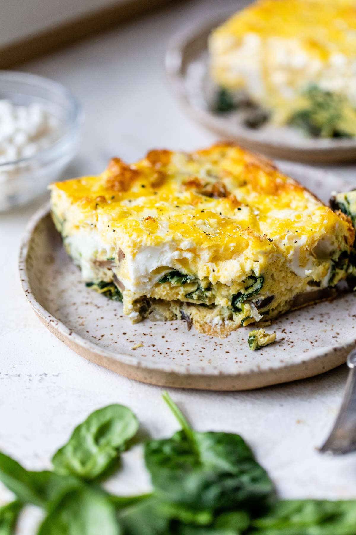 Slice of cottage cheese egg bake on a plate with a bite taken out.