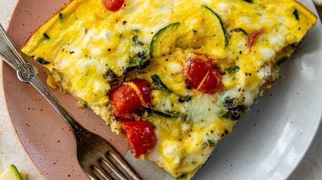 Serving of cottage cheese frittata with tomatoes and zucchini on a plate with a fork.