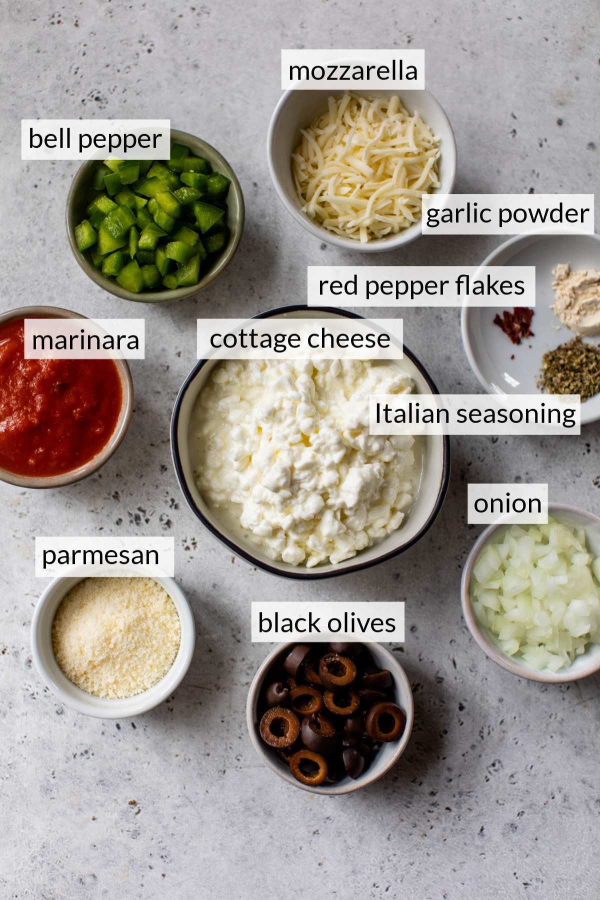 Small bowls with cottage cheese, mozzarella cheese, parmesan, marinara, onions and seasonings.