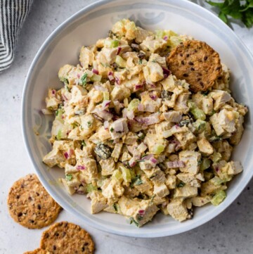 Curry chicken salad in a white bowl with crackers.