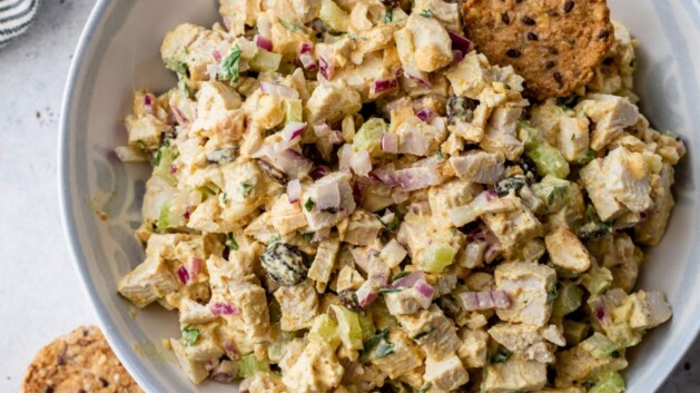 Curry chicken salad in a white bowl with crackers.