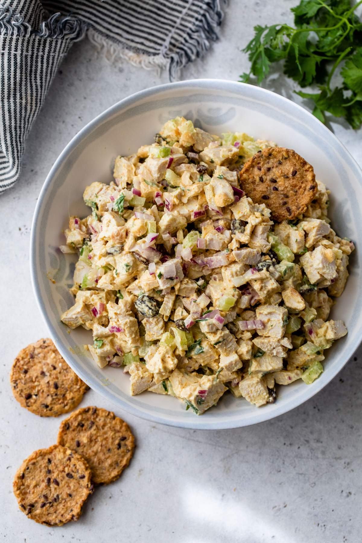 Curry chicken salad in a white bowl with crackers.