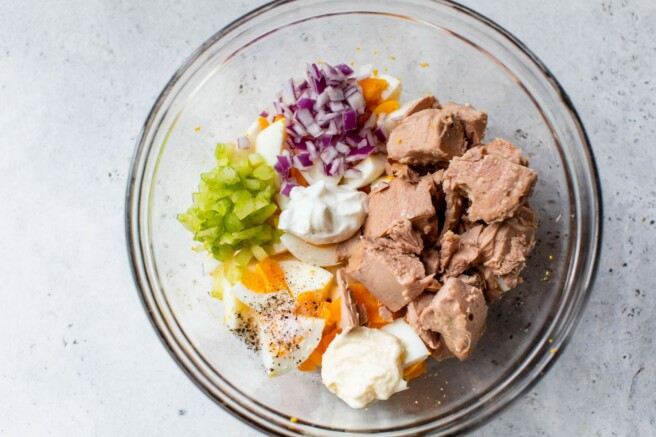 Red onion, tuna and mayo added into a bowl with chopped boiled eggs.