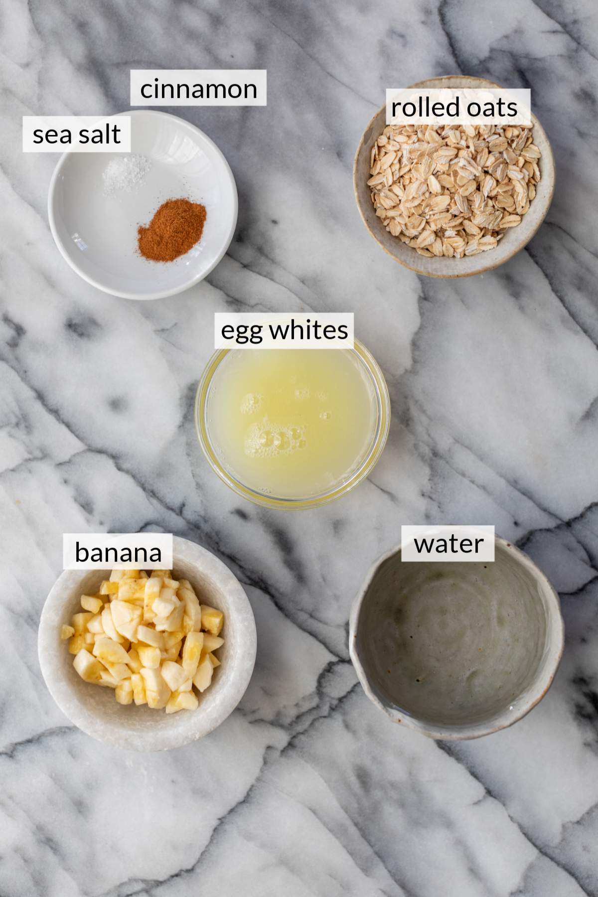 Small bowls with oats, banana chunks, water, and egg whites.