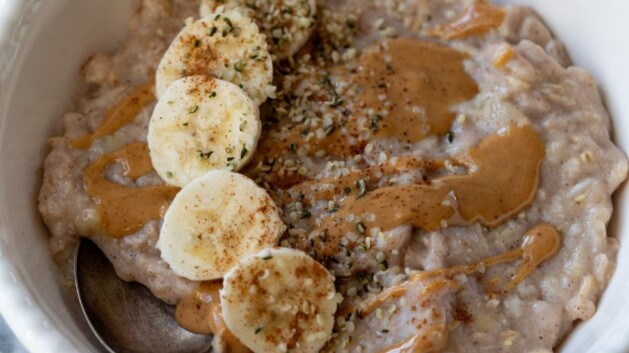 Egg white oatmeal in a white bowl topped with banana slices and almond butter.