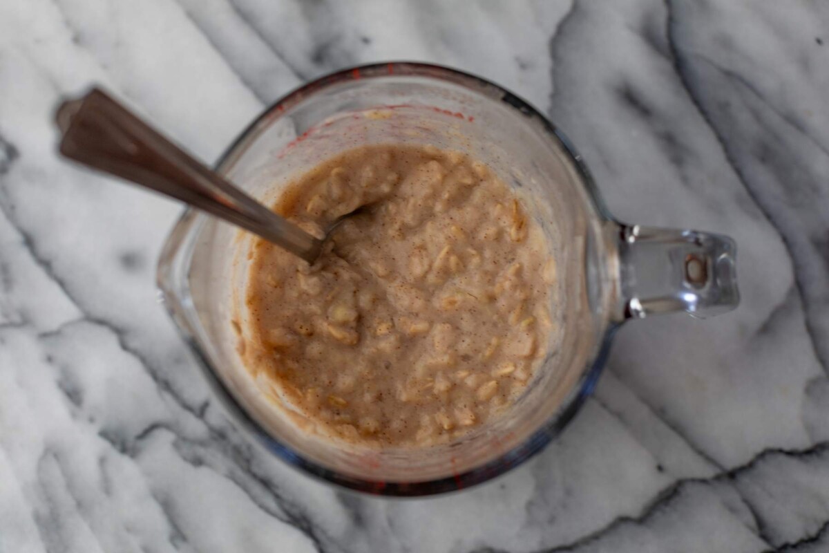 Egg white oatmeal in a spouted glass cup with a spoon.
