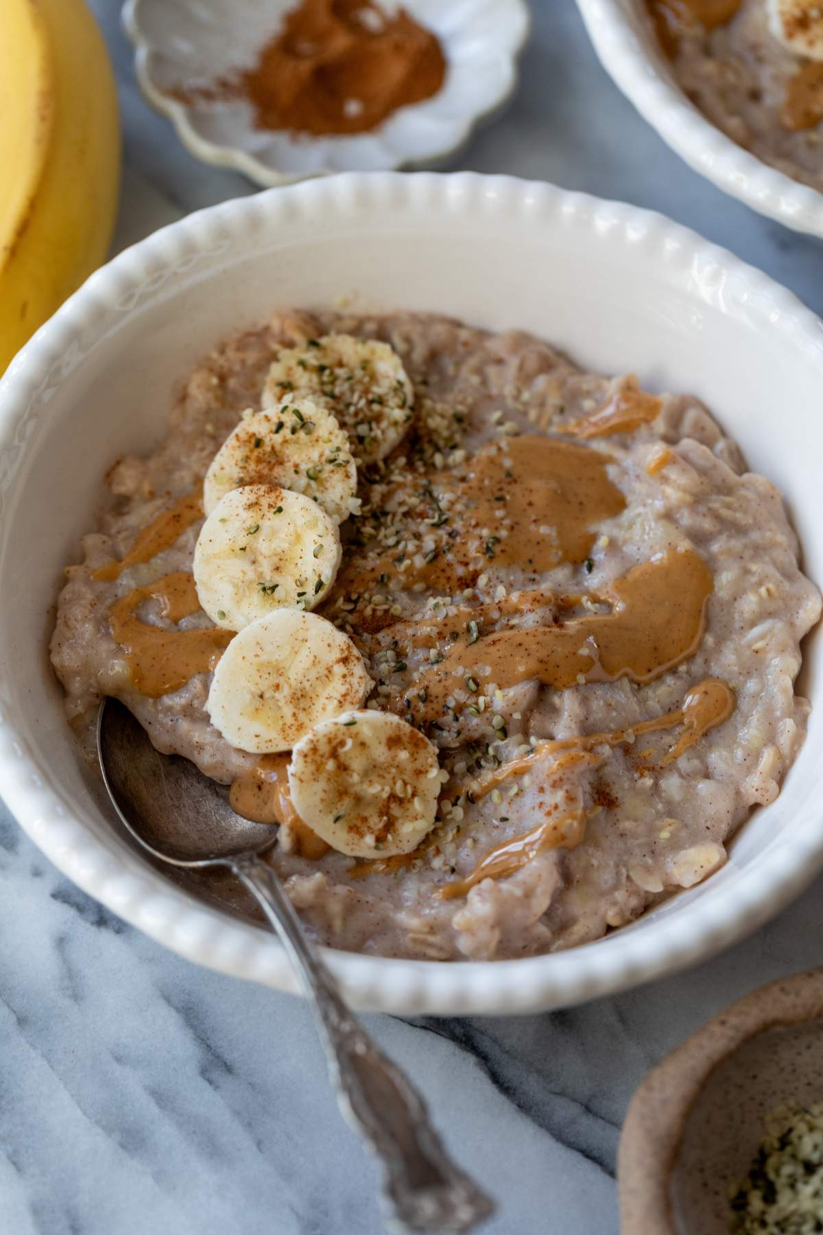 Egg white oatmeal in a white bowl topped with banana slices and almond butter.