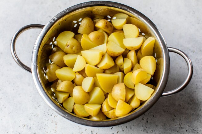 Draining quartered potatoes in a colander.