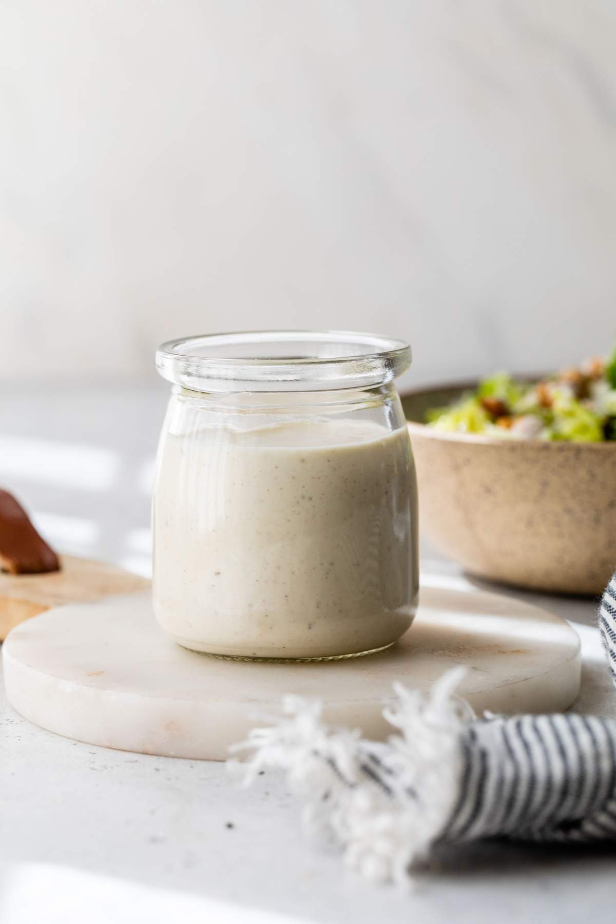 Greek yogurt dressing in a jar near a salad.