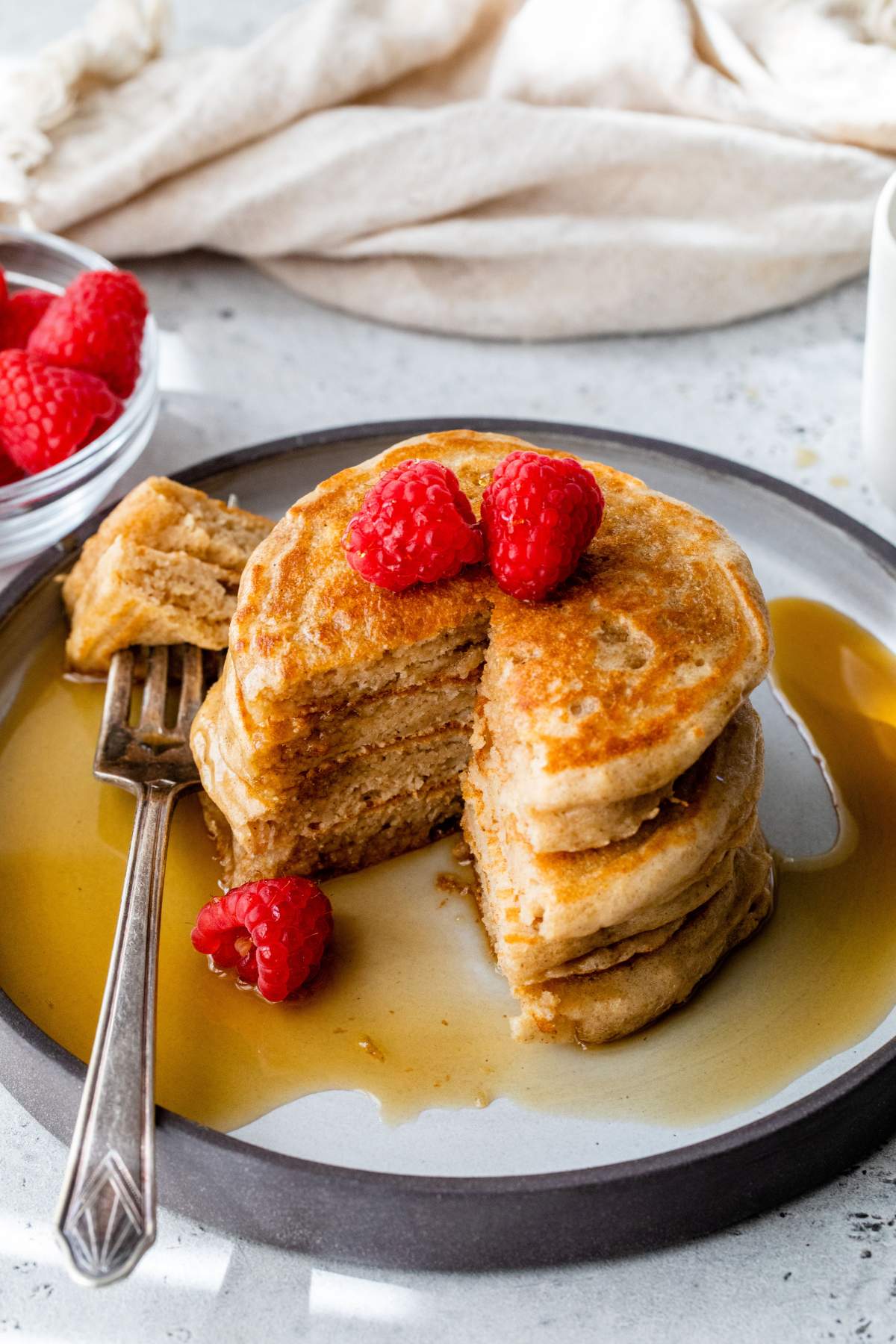 Stack of pancakes with a bite taken out on a fork.