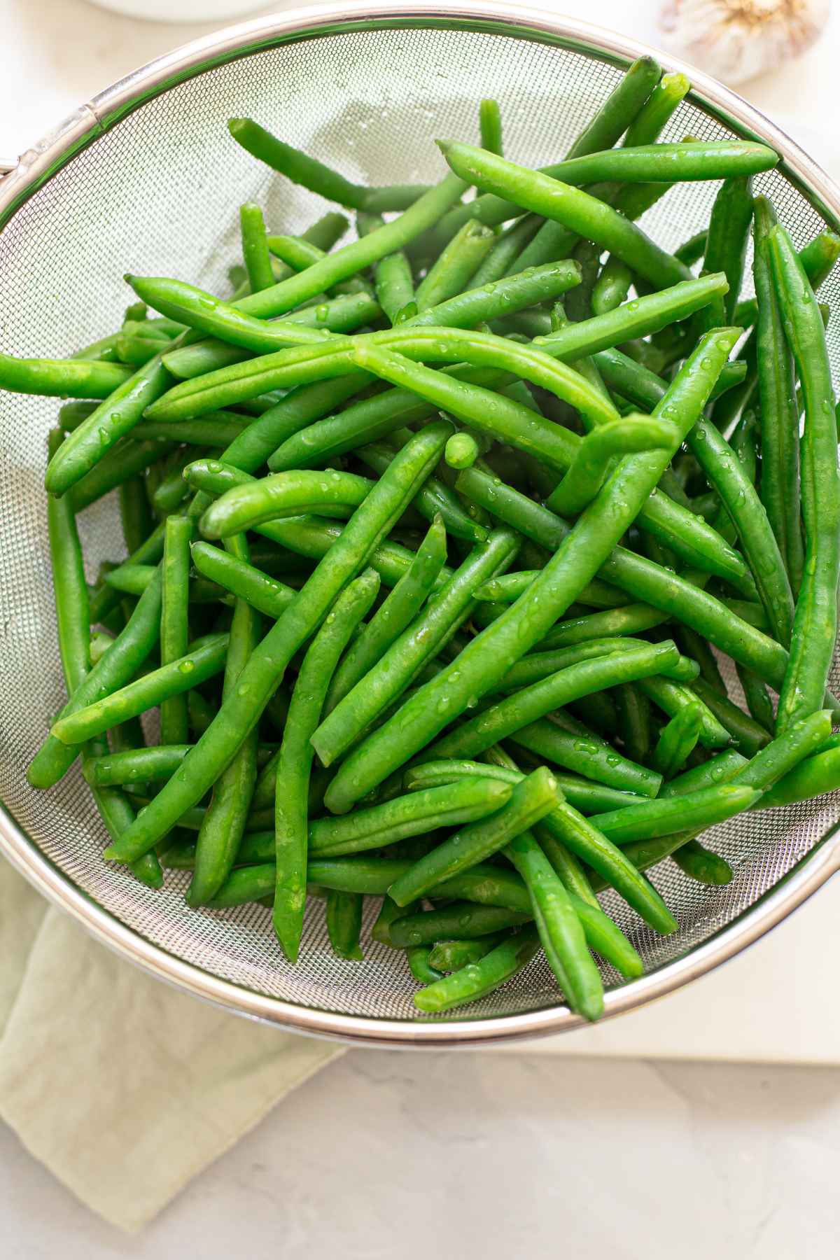 Blanched green beans in a colander.