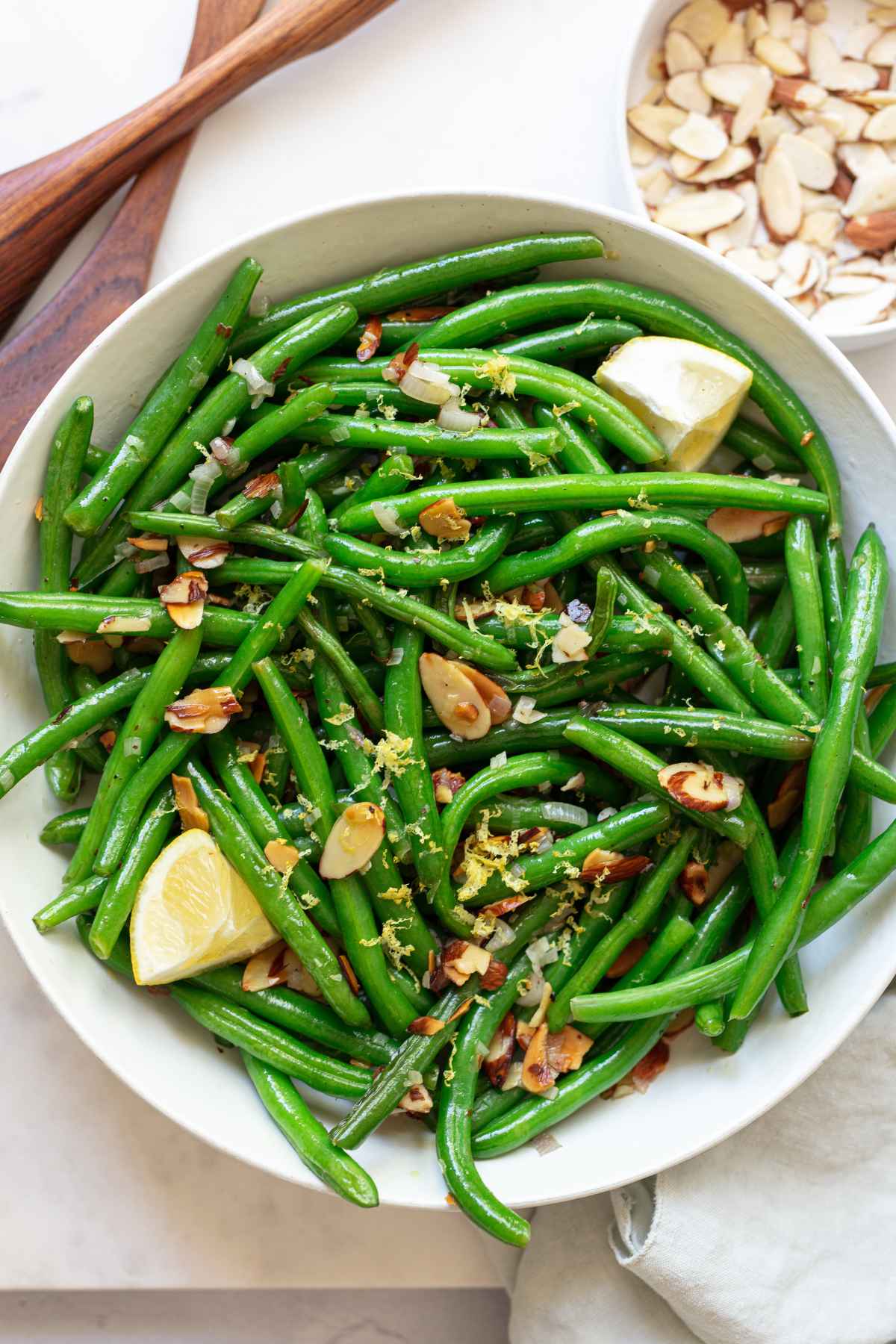 Green beans almondine served with lemon wedges.