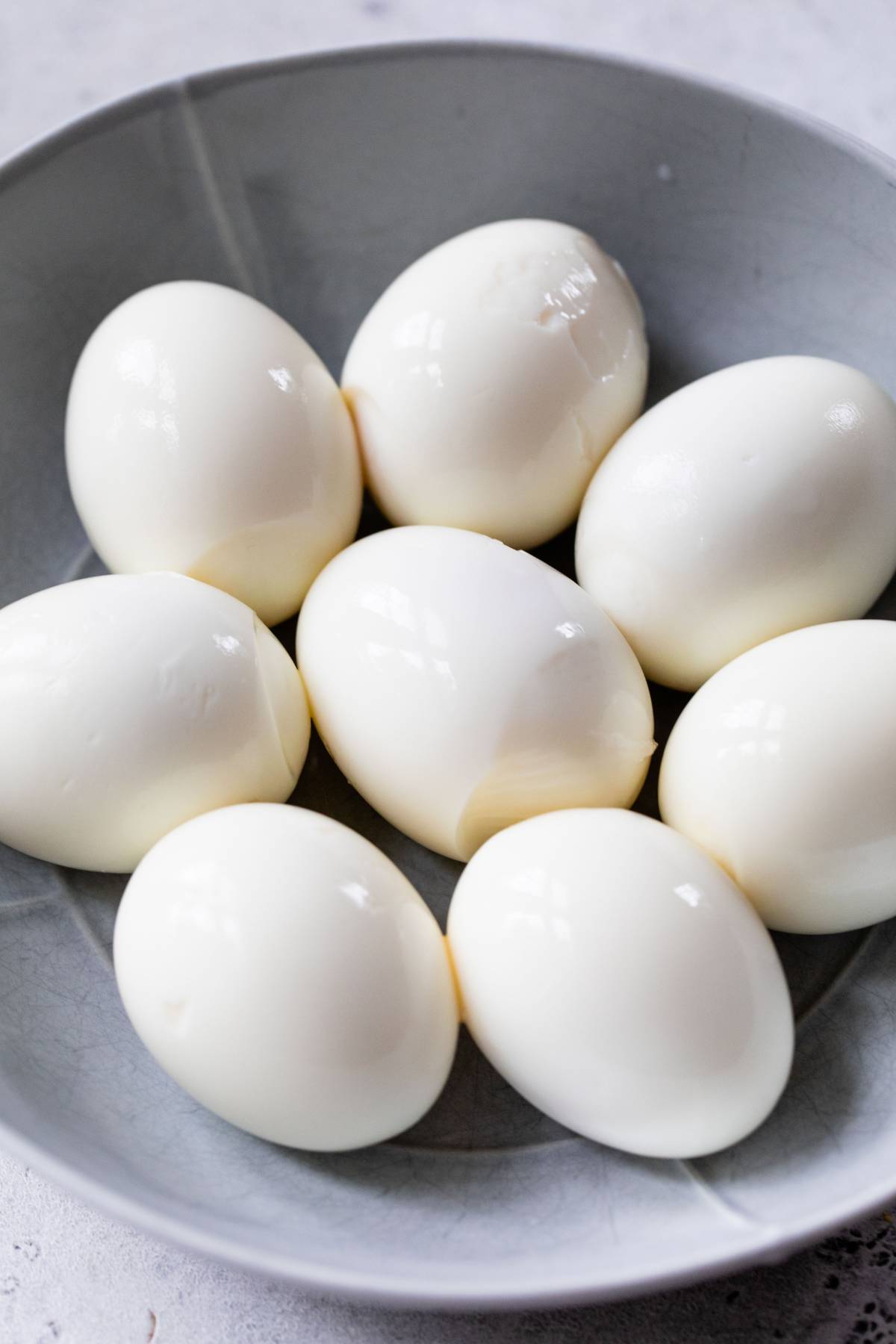 Peeled hard boiled eggs in a bowl.
