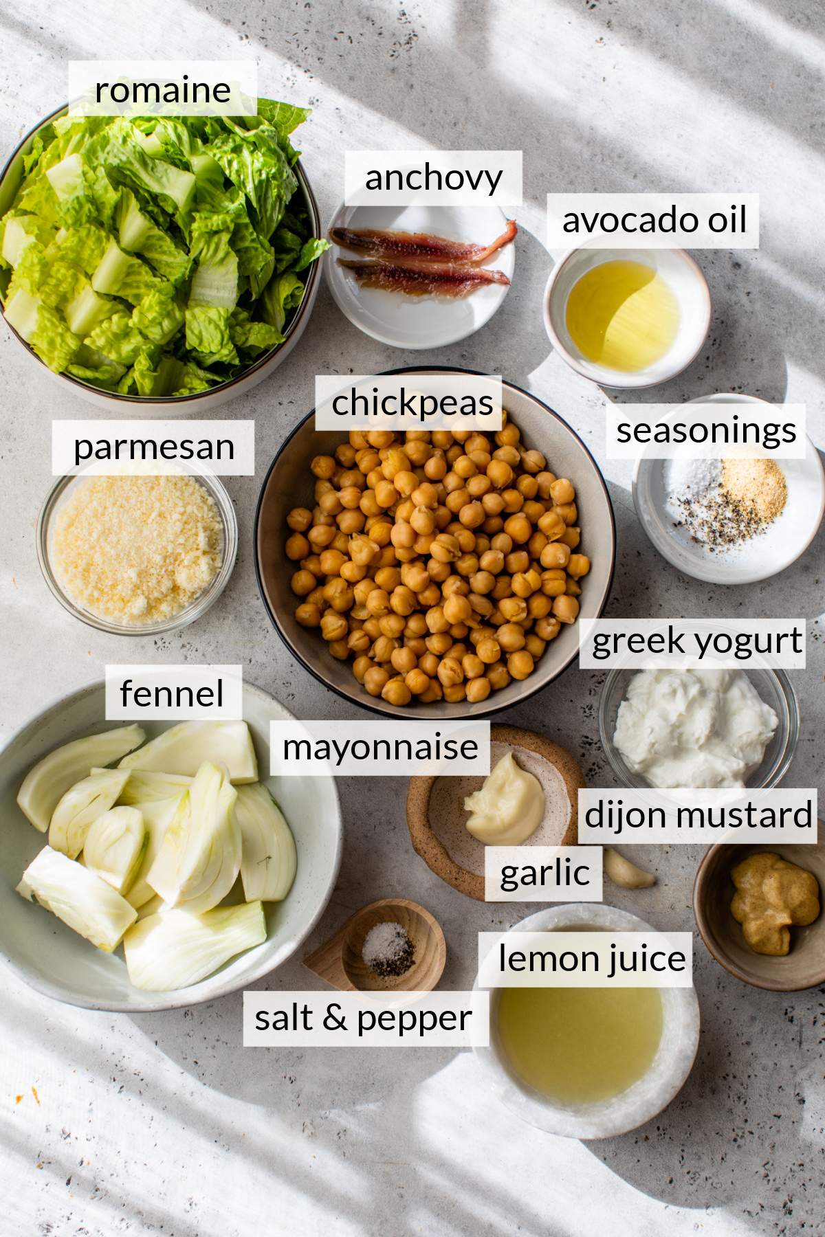 Bowls with lettuce, chickpeas, fennel, mayo, Greek yogurt, cheese and anchovy filets.