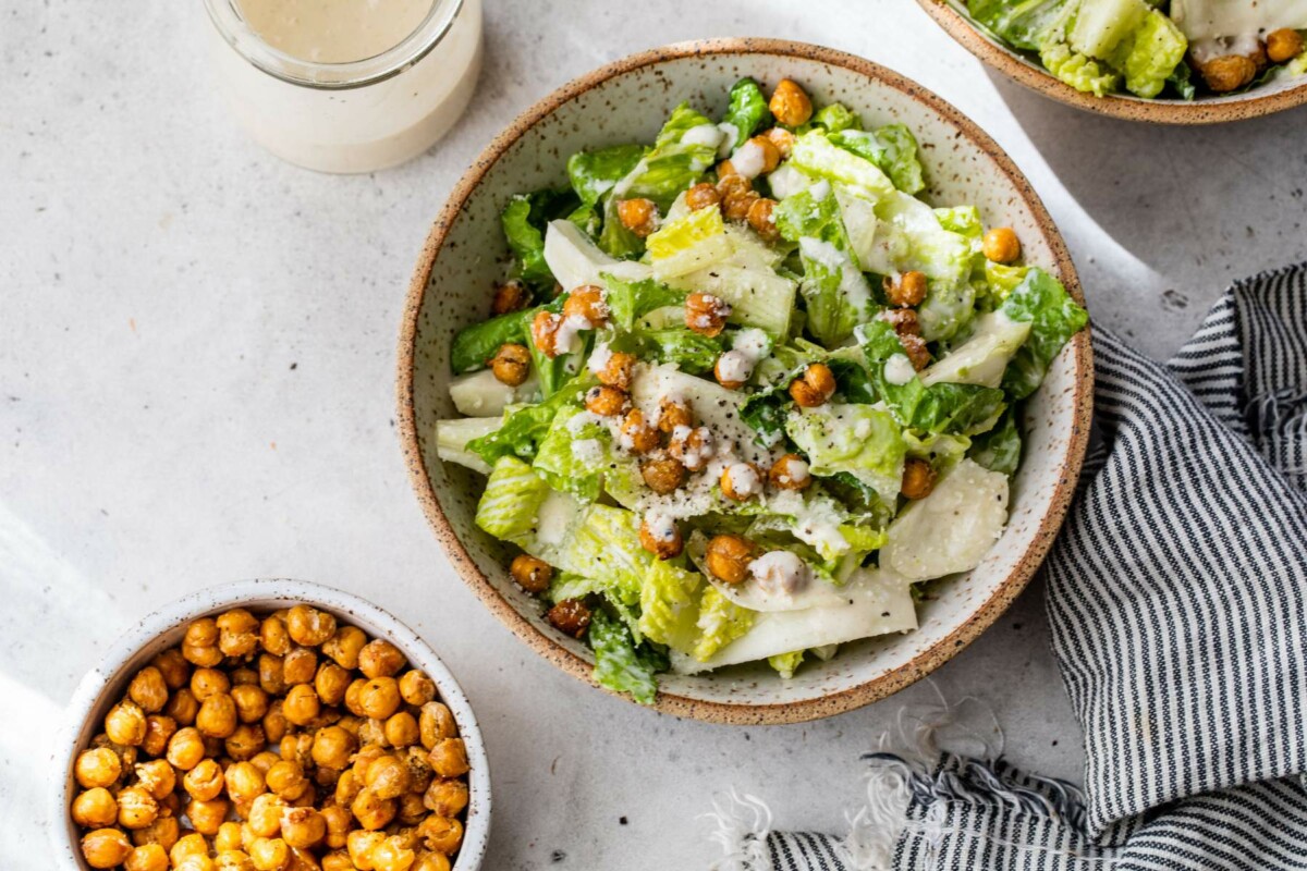 Caesar salad topped with dressing, roasted chickpeas and dressing.