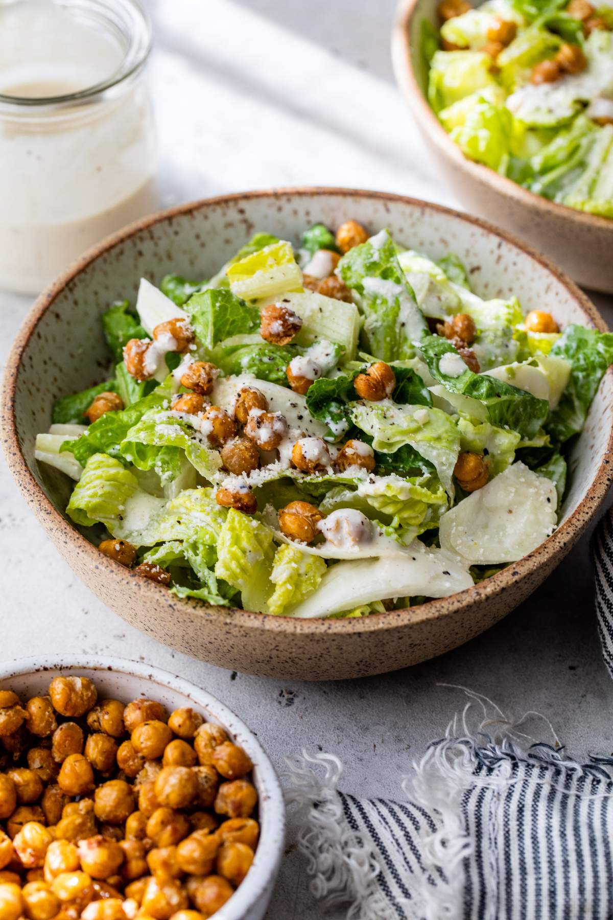 Salad in a bowl with romaine lettuce, roasted chickpeas and dressing.