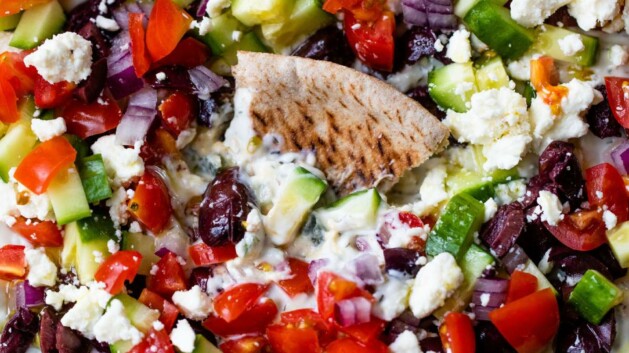 Pita bread in a hummus platter topped with vegetables.