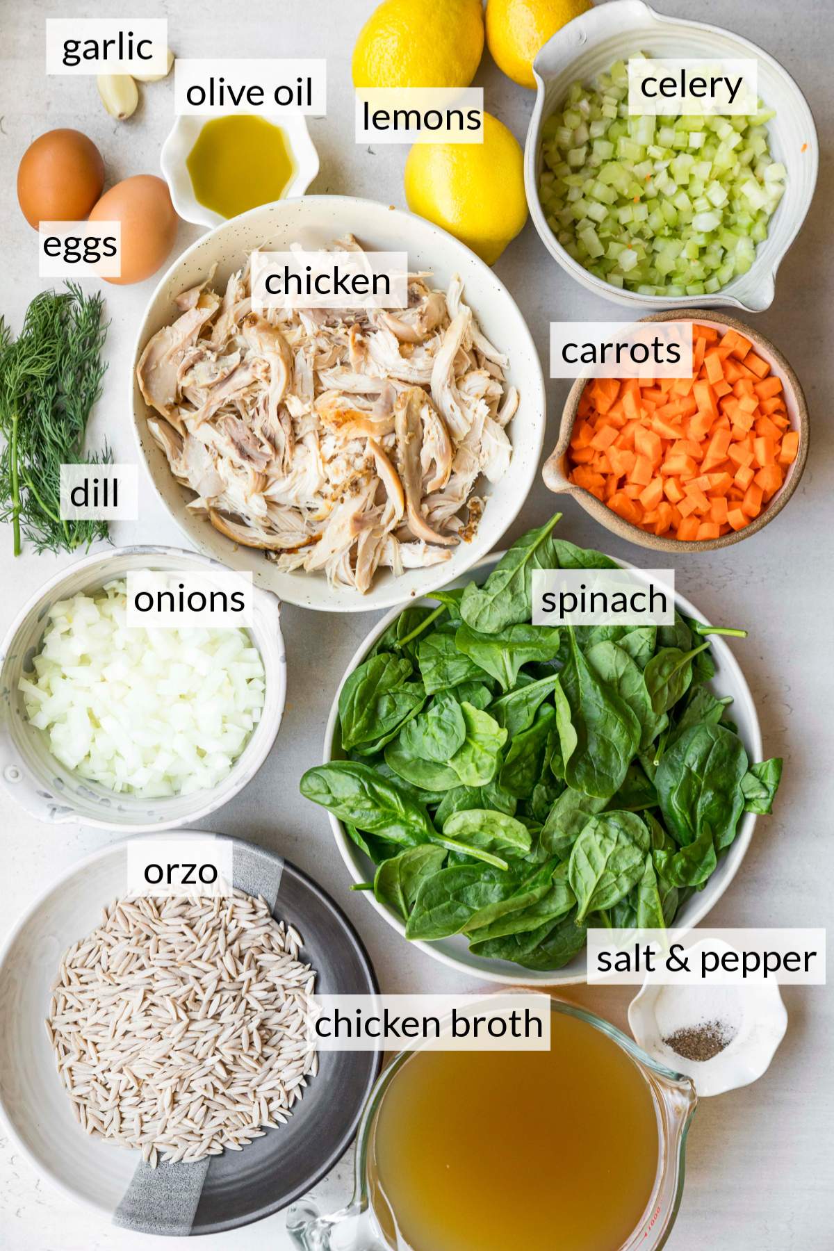 Bowls with shredded chicken, spinach, celery, carrots, onion, and orzo.