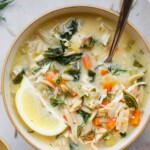 Bowl of lemon chicken soup with a lemon wedge on top.