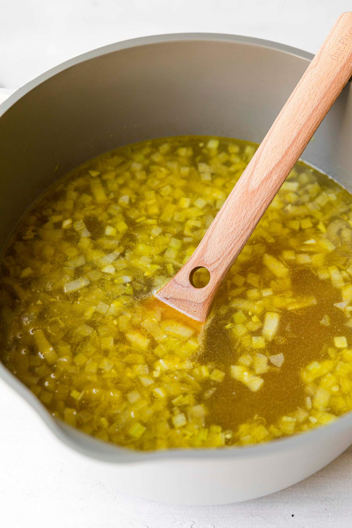 Using a wooden spoon to stir a broth soup.
