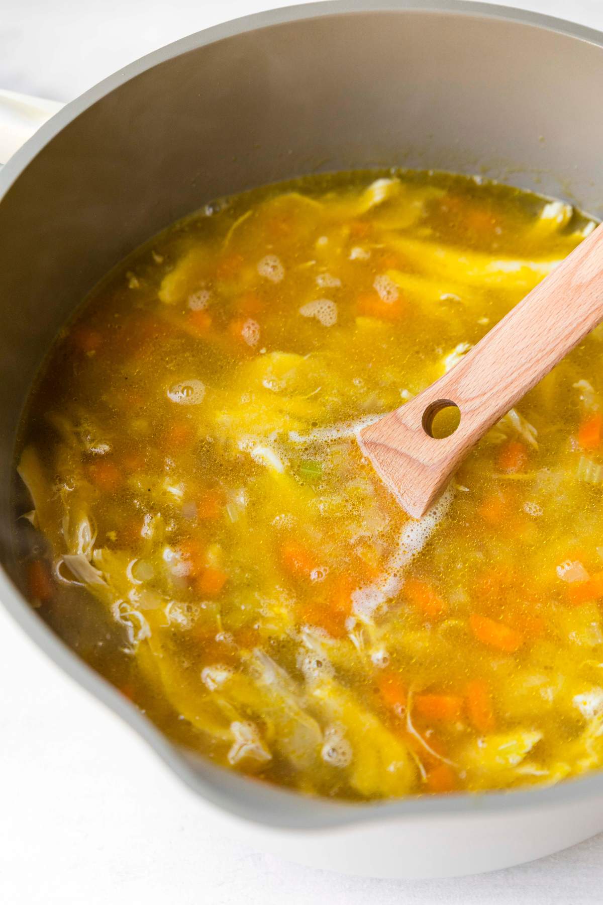 Stirring chicken into a lemon orzo soup.
