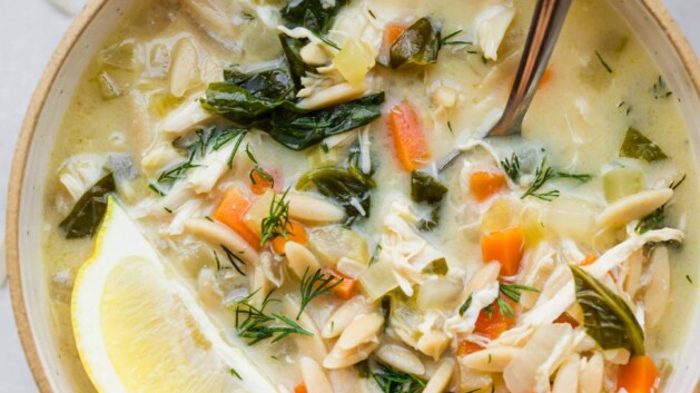 Bowl of lemon chicken soup with a lemon wedge on top.