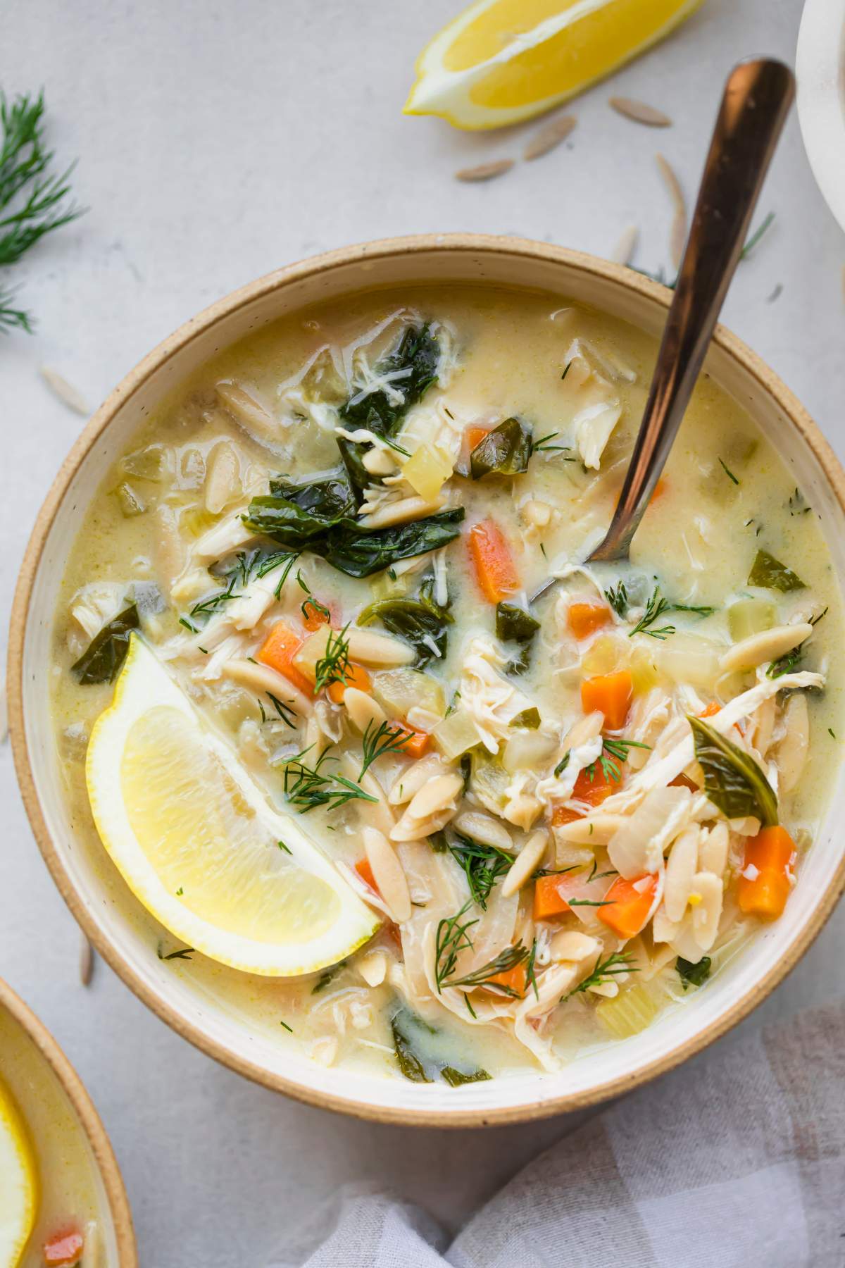 Bowl of lemon chicken soup with a lemon wedge on top.
