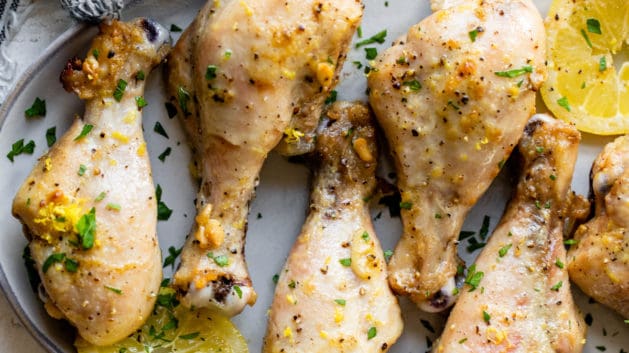 lemon pepper chicken drumsticks on a platter with fresh lemons