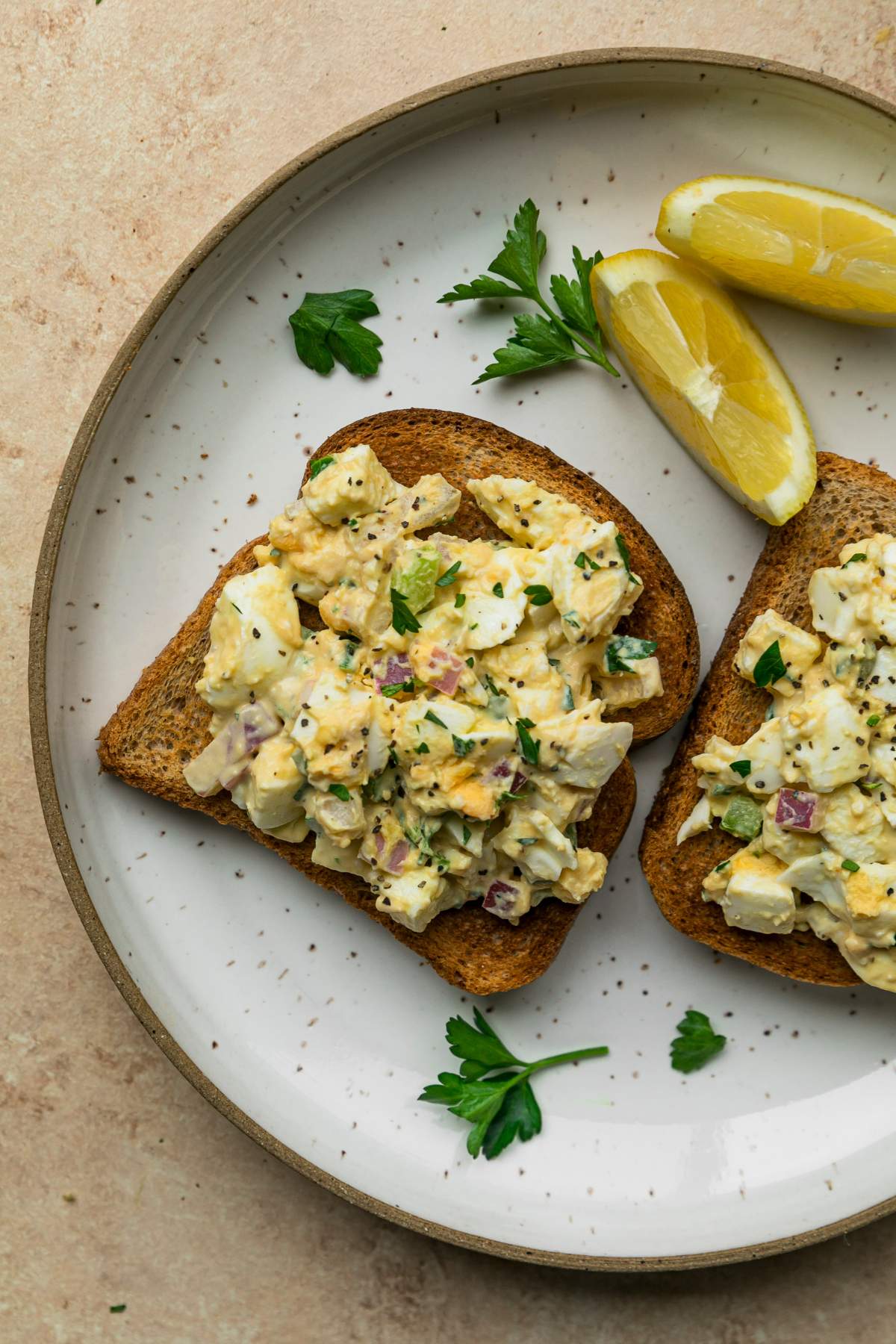Egg salad on slices of bread on a plate.
