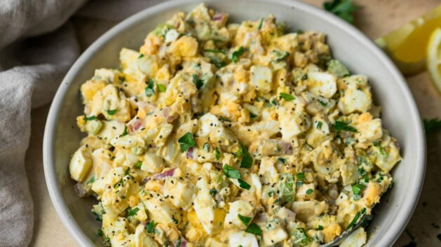 Lightened up egg salad in a bowl near slices of bread.