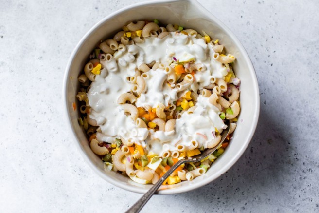 Pouring the dressing over the macaroni salad.
