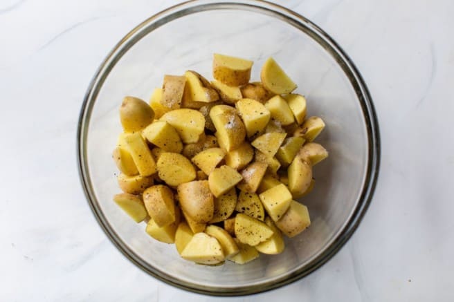 seasoning potatoes in a large bowl