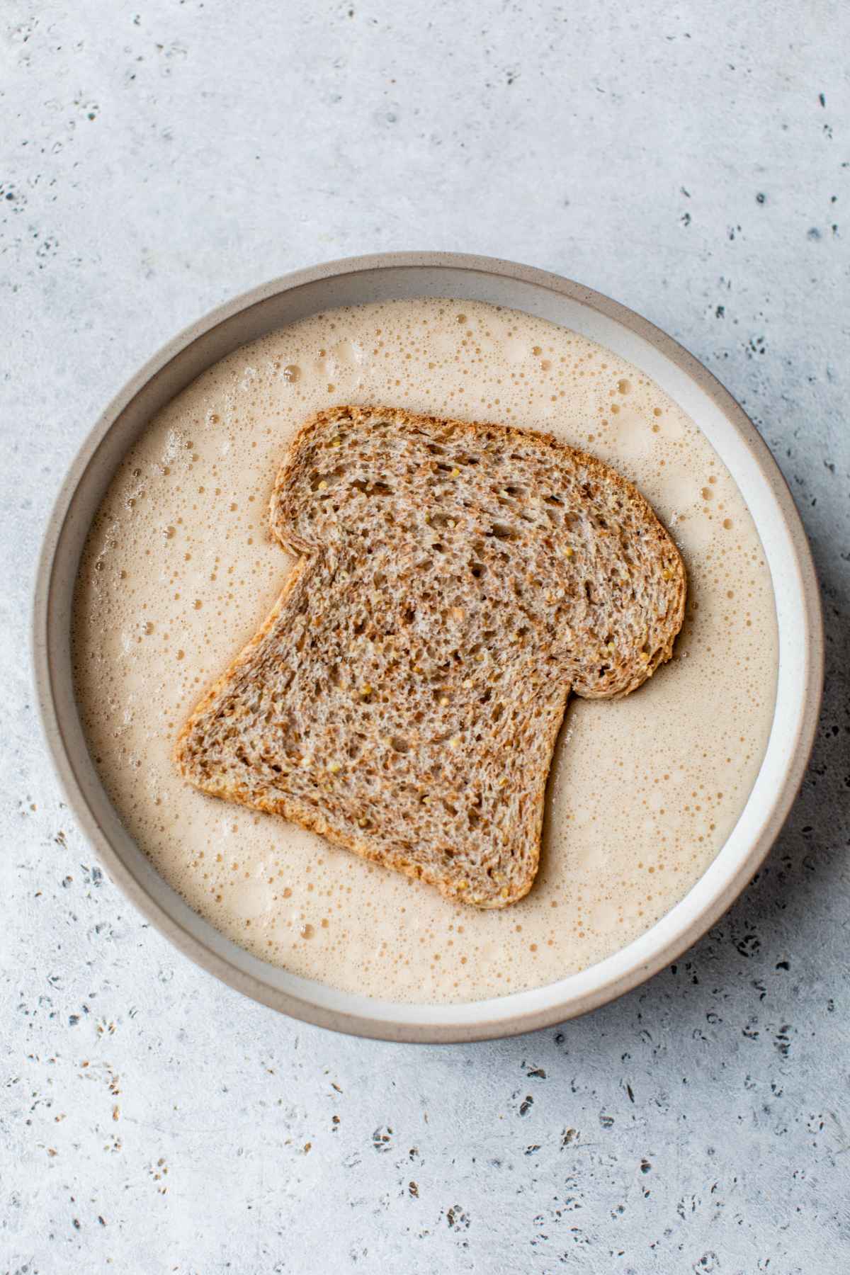 Soaking a slice of bread in a milk and egg mixture.
