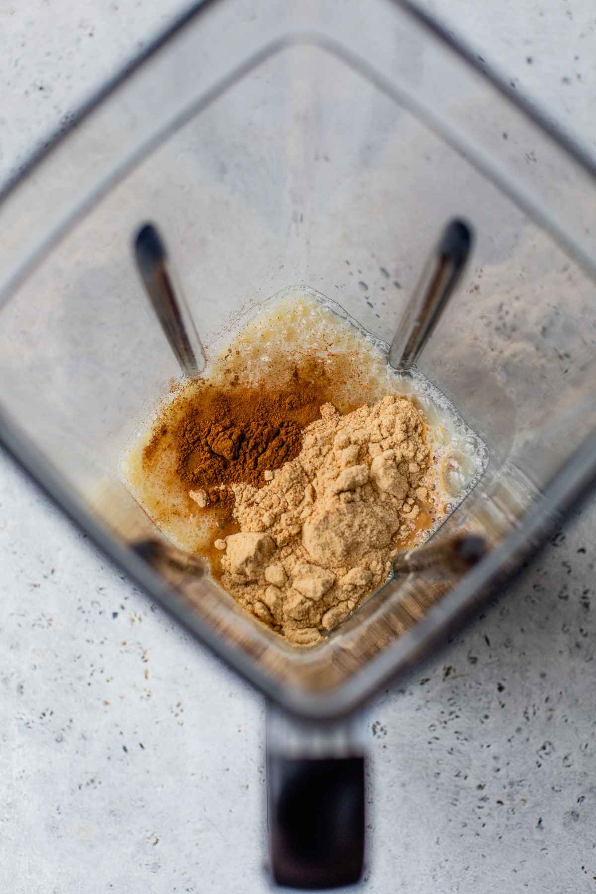Adding protein powder, cinnamon, egg whites and milk to a blender.