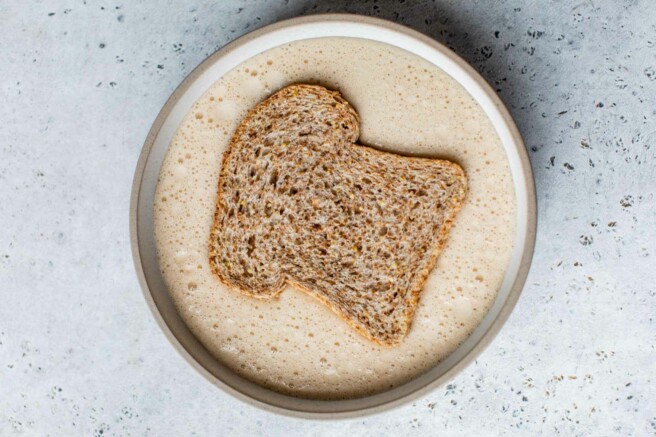 Soaking a slice of bread in a milk and egg mixture.