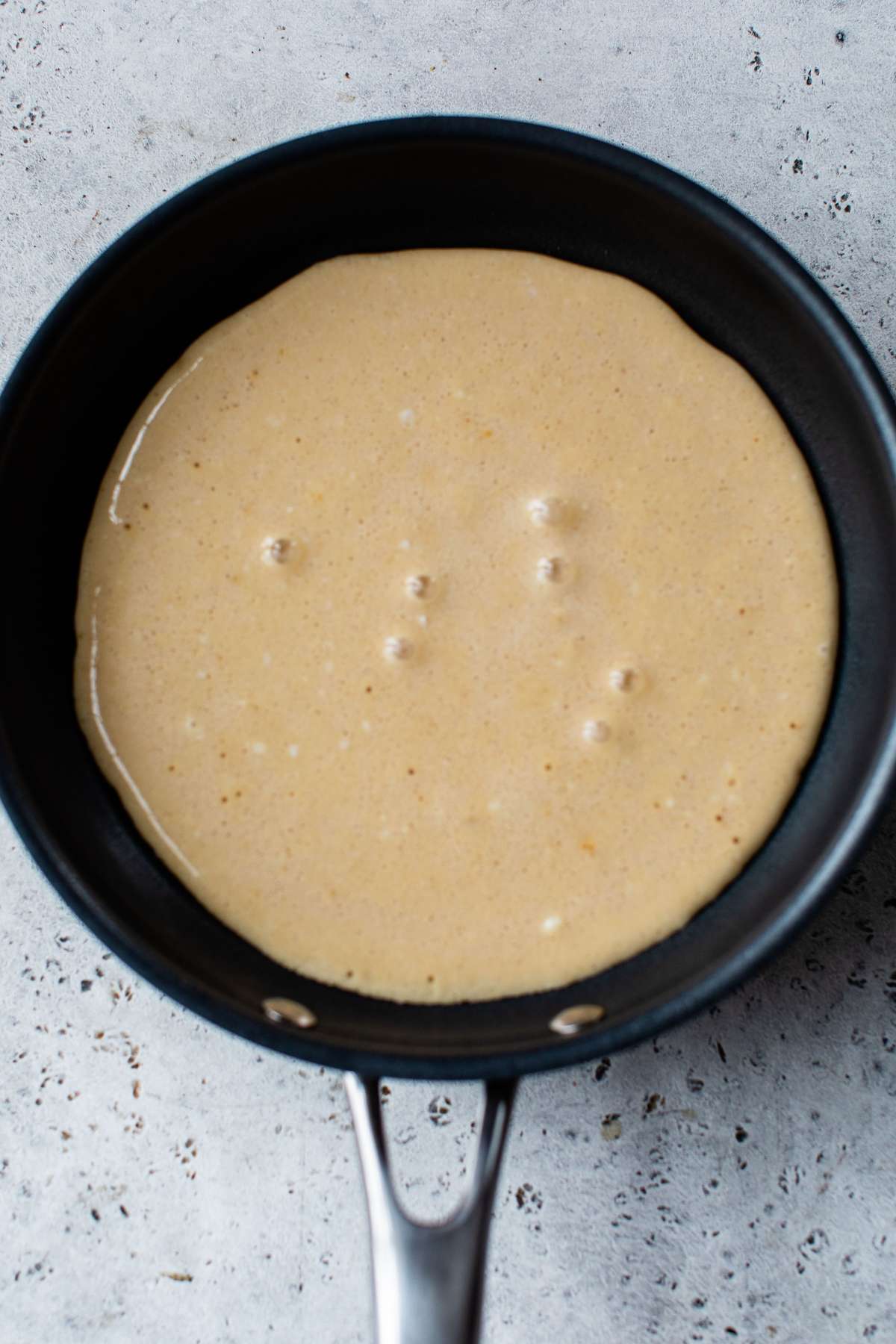 Pancake batter cooking in a skillet.