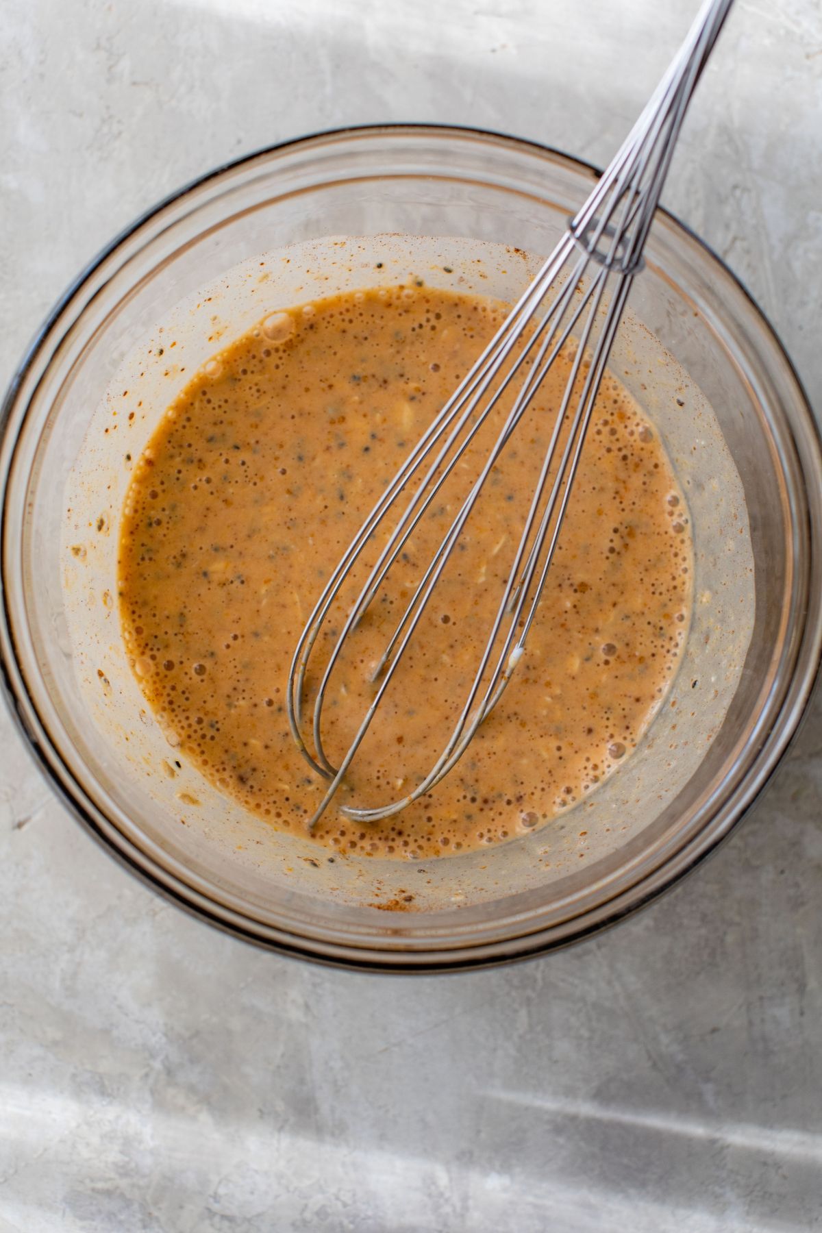Using a whisk to mix pumpkin puree with oats, greek yogurt and milk.