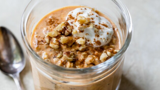 Pumpkin overnight oats in a glass jar topped with nuts and yogurt.