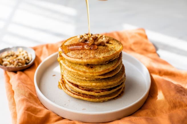 drizzle maple syrup over a stack of pancakes